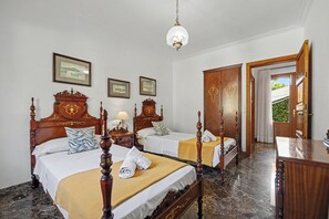 A hotel room with two wooden beds, a marble floor, a wooden wardrobe, and a door leading to a balcony.
