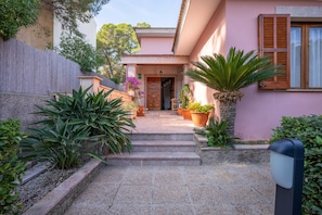 A building with a pink facade, a wooden door, and a staircase leading to the entrance.
