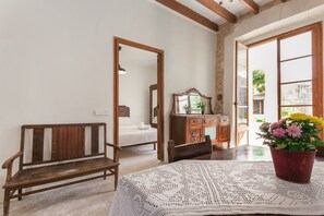 A room with a wooden bench, a bed, a dresser, and a table with a crocheted tablecloth.