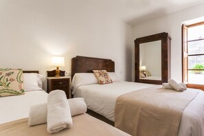 Une chambre d’hôtel avec deux lits, une table de chevet avec une lampe, un grand miroir et une fenêtre donnant sur un beau paysage.
