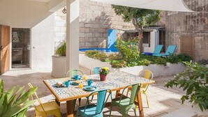 A patio with a table set for breakfast, outdoor seating, and a stone wall backdrop. - Holiday Home Sa Lluna Blava with Pool & Wi-Fi (Santa Margalida)