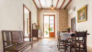 A room with a wooden bench, a table with chairs, a stone wall, and a door leading outside. - Holiday Home Sa Lluna Blava with Pool & Wi-Fi (Santa Margalida)