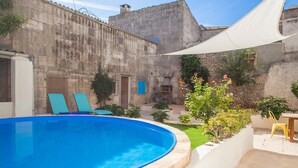 A swimming pool with lounge chairs, a stone building, and a pergola providing shade. - Holiday Home Sa Lluna Blava with Pool & Wi-Fi (Santa Margalida)