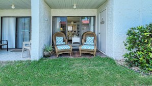 A two-story building with a covered entrance, two wicker chairs with patterned cushions, a small table, and a potted plant. - Runaway Bay Resort by BBG (Bradenton Beach)