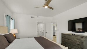 A bedroom with a bed, a dresser, a ceiling fan, a TV, and a bathroom visible through an open door. - Sago Sands 302 - 2340381 (Santa Rosa Beach)