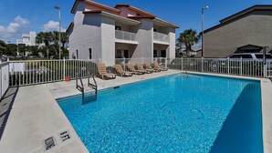 A swimming pool with lounge chairs and a building with balconies. - Sago Sands 302 - 2340381 (Santa Rosa Beach)