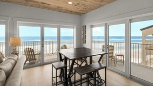 A spacious room with a wooden ceiling, large sliding glass doors leading to a balcony with a view of the ocean. - Sago Sands 302 - 2340381 (Santa Rosa Beach)