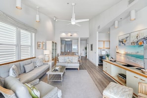 A spacious living area with a sofa, coffee table, and ottoman, a kitchen with a large island, and a dining area with chairs and a table. - Harbor Villa Club 312 (Longboat Key)