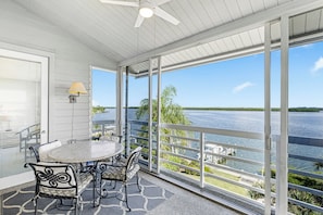 A balcony with a table and chairs, a ceiling fan, and a view of a body of water. - Harbor Villa Club 312 (Longboat Key)