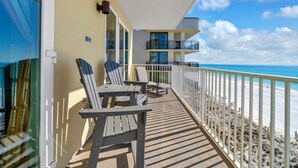 A balcony with two chairs and a table, overlooking a beach with a clear sky. - Sea Dunes 501 (Fort Walton Beach)