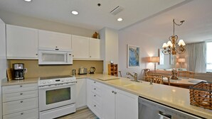 A modern kitchen with white cabinetry, a built-in microwave, a coffee maker, and a dishwasher. - Harbor Villa Club 206 - 2129044 (Longboat Key)