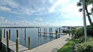 A wooden dock extending into calm water, with a concrete walkway alongside. - Harbor Villa Club 206 - 2129044 (Longboat Key)