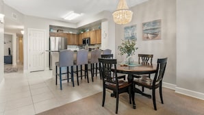 A modern kitchen with wooden cabinets, a stainless steel refrigerator, and a chandelier. - Sunrise Resort by BBG (Panama City Beach)
