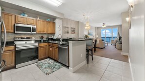 A modern kitchen with stainless steel appliances, wooden cabinets, and a large island. - Sunrise Resort by BBG (Panama City Beach)