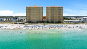 Ein Hotel direkt am Strand mit zwei markanten Türmen, einem Sandstrand und klarem türkisblauem Wasser.