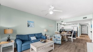 Ein Wohnzimmer mit einem blauen Sofa, einem Couchtisch und einem Deckenventilator.
