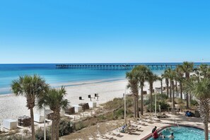 A beach resort with a pool, palm trees, and a pier in the background. - Calypso Resort by Best Beach Getaways (Panama City Beach)