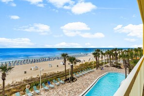 A beach view with a pool, palm trees, and a pier in the distance. - Calypso Resort by Best Beach Getaways (Panama City Beach)