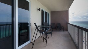 A balcony with a table and chairs, a sliding glass door, and a view of the ocean. - Sunrise Resort by BBG (Panama City Beach)