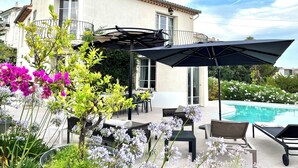 A poolside area with outdoor seating, a pergola, and a view of a swimming pool. - CANNES VILLA SWIMMING POOL, SEA VIEW,15 MN PALAIS DU FESTIVAL,1 MN BEACH ON FOOT (Cannes)