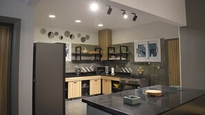 A modern kitchen with a central island, built-in appliances, and decorative wall plates. - Egypt 5 - STAR Cozy 3 BR Villa with Garden (First 6th of October)