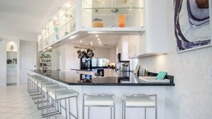 A modern kitchen with a central island, bar stools, and upper cabinets. - Vaca Cut Sunsets 5 bed 4 bath home with pool Gulf Views on Vaca Cut (Marathon)