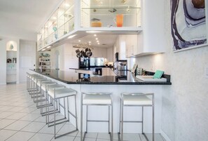 A modern kitchen with a central island, bar stools, and upper cabinets. - Vaca Cut Sunsets 5 bed 4 bath home with pool Gulf Views on Vaca Cut (Marathon)