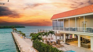 A resort with a pool, outdoor seating, and a view of the sea at sunset. - Vaca Cut Sunsets 5 bed 4 bath home with pool Gulf Views on Vaca Cut (Marathon)