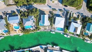 Luftaufnahme eines Küstenresorts mit mehreren Gebäuden, einer Marina und einem großen, grünen Poolbereich.