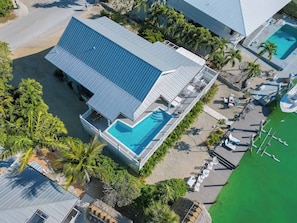 Vue aérienne d’un complexe hôtelier comprenant une piscine, une jetée et une plage.