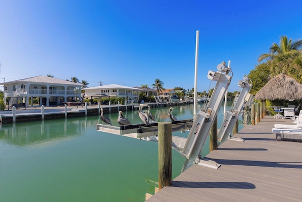 A waterfront property with a dock, a thatched-roof structure, and a building with balconies.