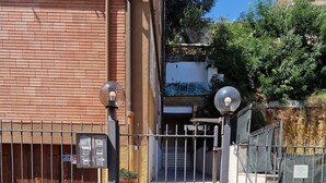 Una entrada protegida con un portón metálico, un muro de ladrillo y un cartel con el número 20.