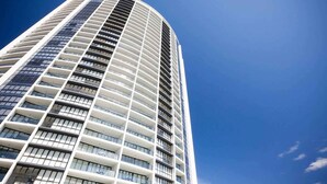 Un edificio alto y moderno con fachada curva y múltiples balcones.