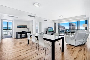 Een moderne woonkamer met een eethoek, grote ramen en uitzicht op een stadsgezicht.