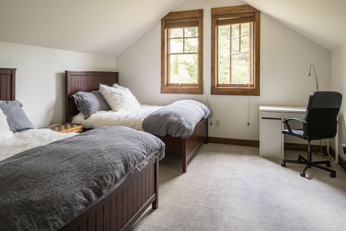 A bedroom with two beds, a desk, and a chair.