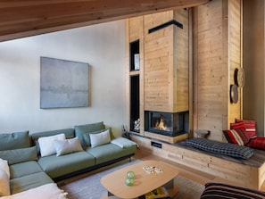 Un salon chaleureux avec un canapé vert, une cheminée en bois et un tableau abstrait accroché au mur.