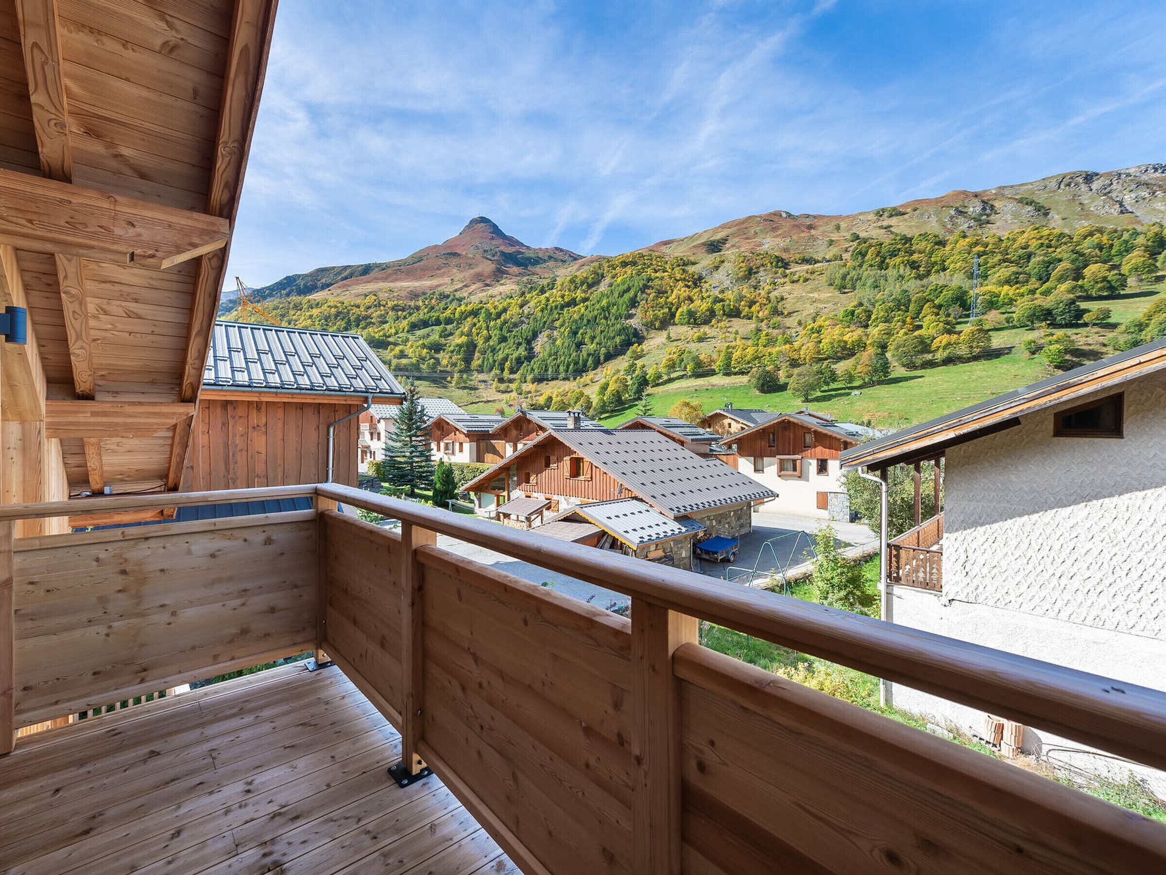Un balcon en bois donnant sur un paysage montagneux, avec des bâtiments de style chalet traditionnel.