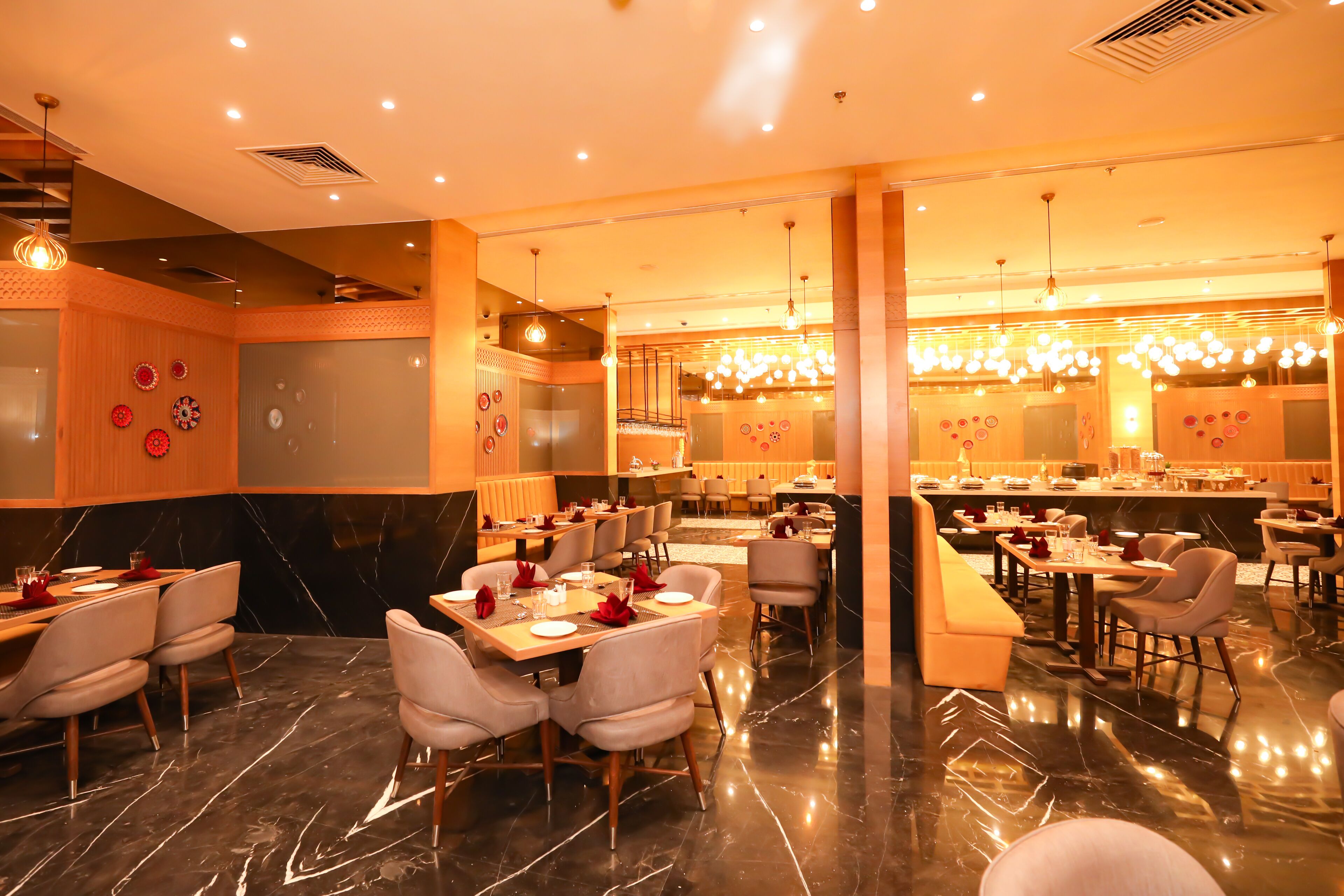 A spacious restaurant with high ceilings, modern lighting, and a polished marble floor.