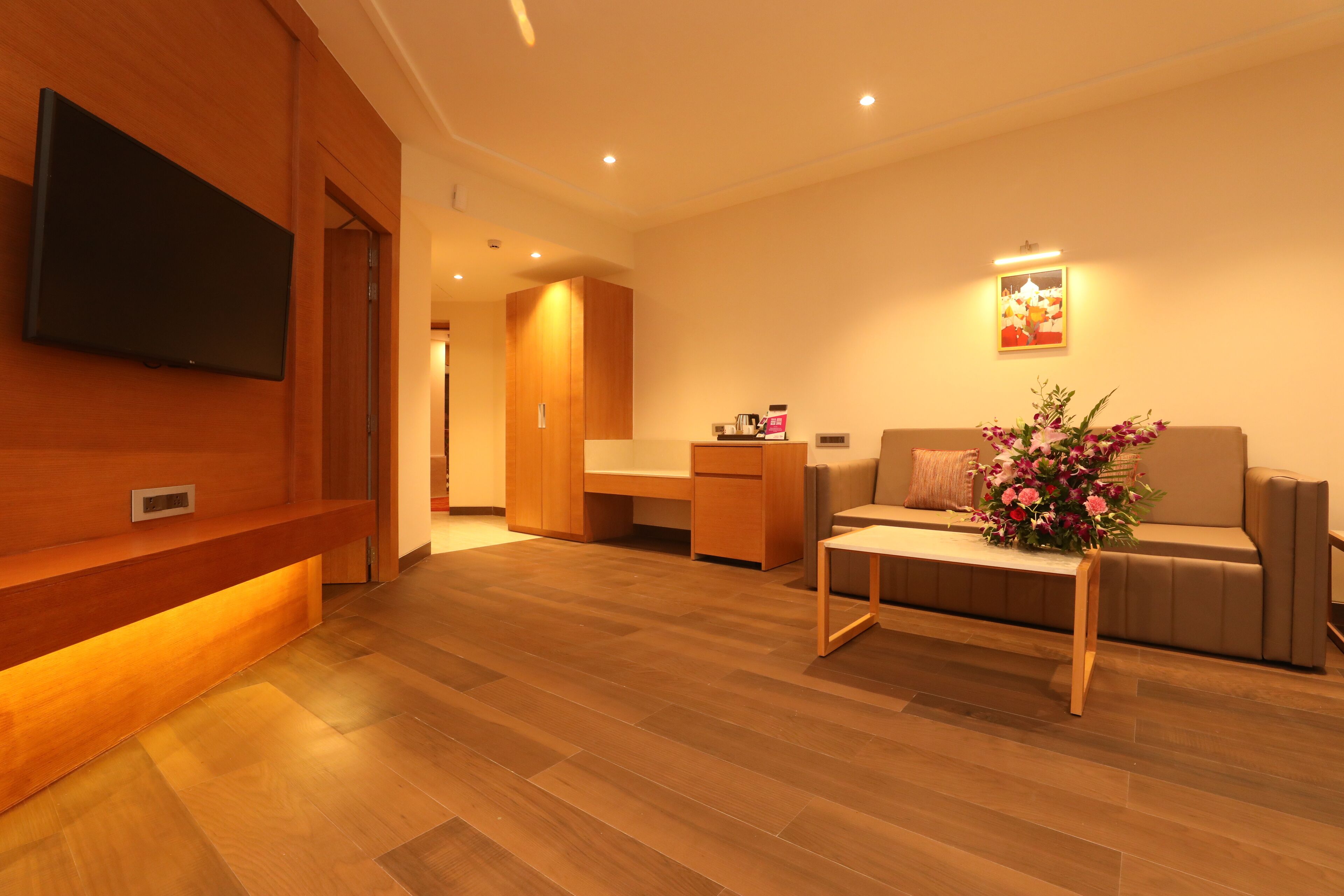 A modern living room with a wooden reception desk, a sofa, and a flat-screen TV mounted on the wall.