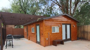 Une cabane en bois dotée d’une terrasse, d’un barbecue et d’un espace salon abrité.