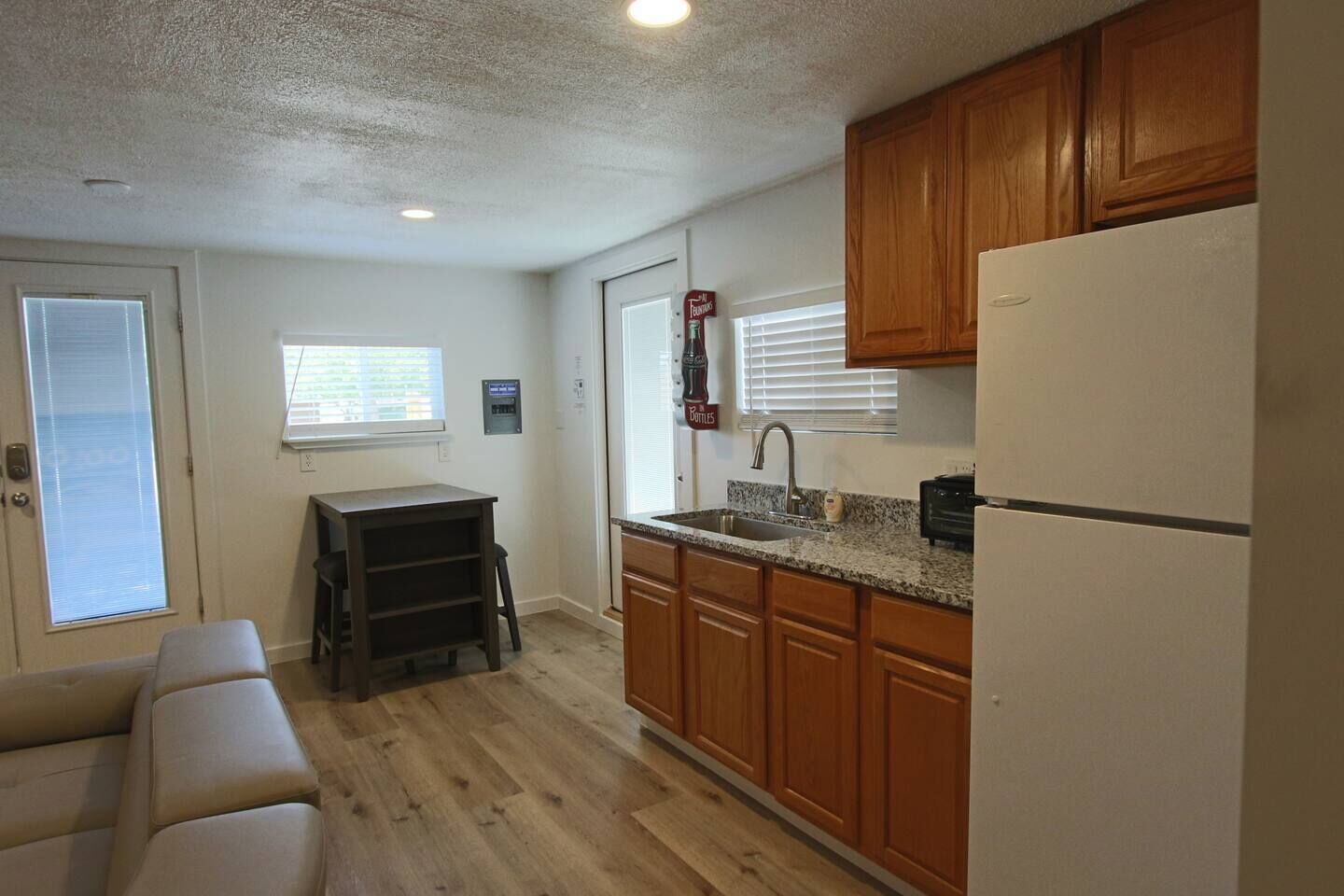 A compact kitchen with wooden cabinets, a built-in refrigerator, and a countertop sink.