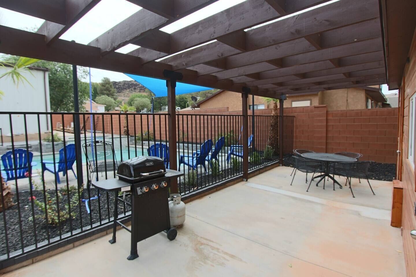 An outdoor patio with a grill, chairs, and a table.