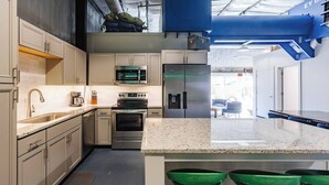 A modern kitchen with stainless steel appliances, a granite countertop, and green bar stools. - Area 51 | Private Micro Pool-Resort | Pets OK (Hurricane)