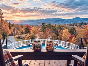 A wooden deck with two mugs on a railing overlooking a swimming pool and a mountainous landscape. - 10 min to Soaky mntns & shoping, private backyard (Sevierville)
