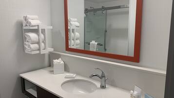 Uma casa de banho moderna com uma pia branca, um espelho grande com moldura vermelha e um porta-toalhas com toalhas dobradas.