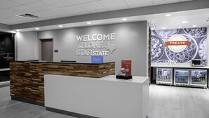 A hotel reception area with a wooden reception desk, a 'Welcome to the Lone Star' sign, and a 'Treats' section with snacks and drinks. - Hampton Inn & Suites Cedar Park North Austin (Cedar Park)