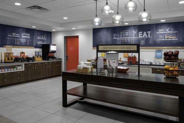 A breakfast area with a counter, kitchen appliances, and a wall with a 'Happy Breakfast Starts Here' sign.