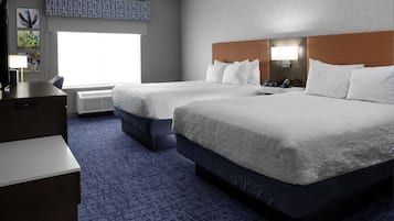 Una habitación de hotel con dos camas, un escritorio, una silla, una lámpara y un ventanal grande.