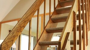 Eine Holztreppe mit Handlauf, Teppichstufen und einem gemusterten Teppich auf der Landung.