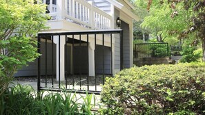 Ein Haus mit überdachter Veranda, weißen Geländern und einem Garten mit verschiedenen Pflanzen und Sträuchern.
